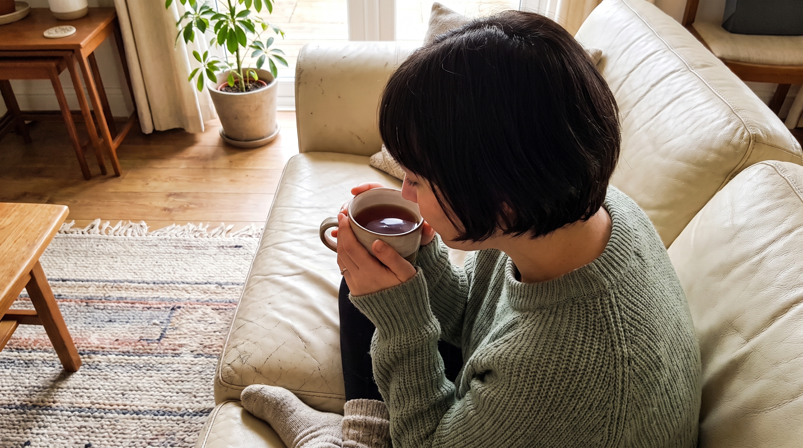 Person sitting quietly on a sofa with a cup of tea