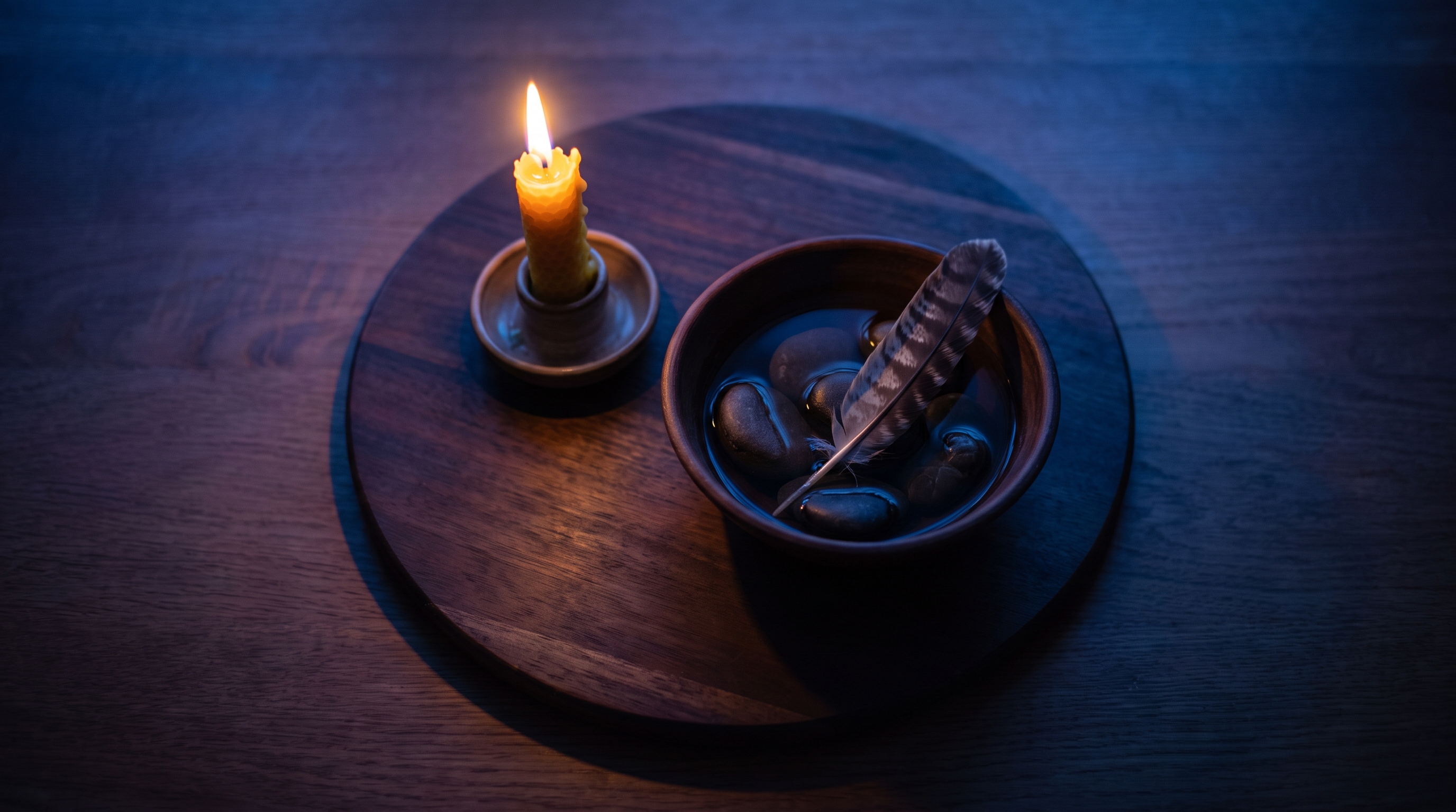 four candles water stones feather arranged on wooden table