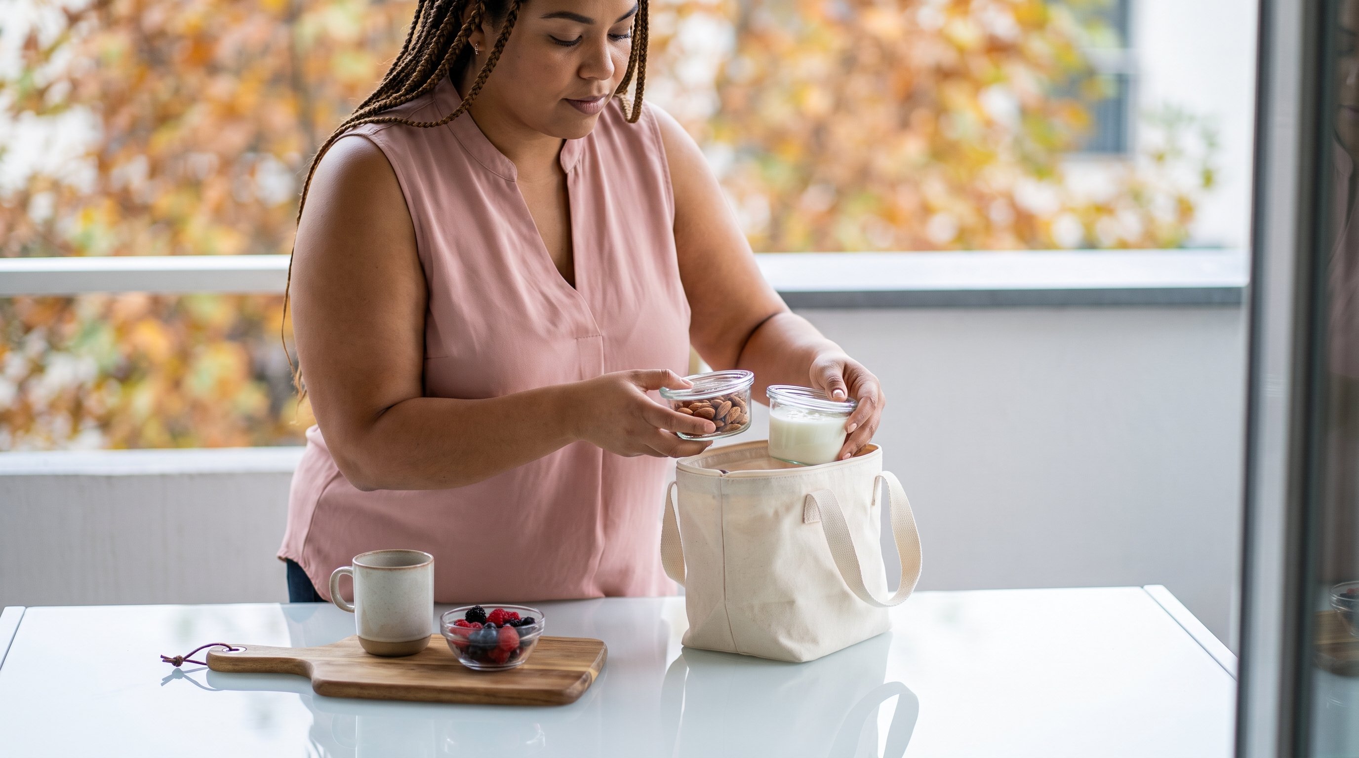 person packing yoghurt and almonds into a lunch bag