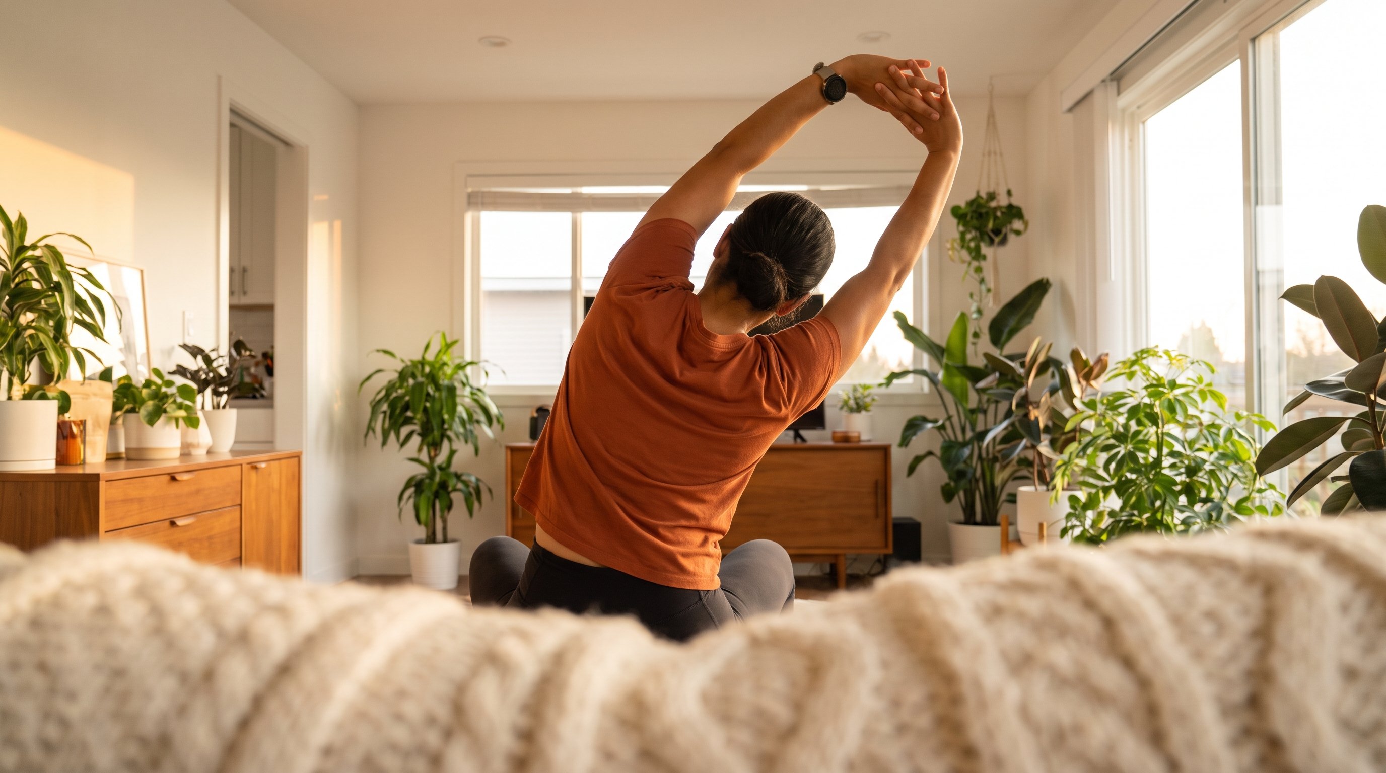 woman stretching arms overhead by a sunny window woman stretching arms overhead by a sunny window