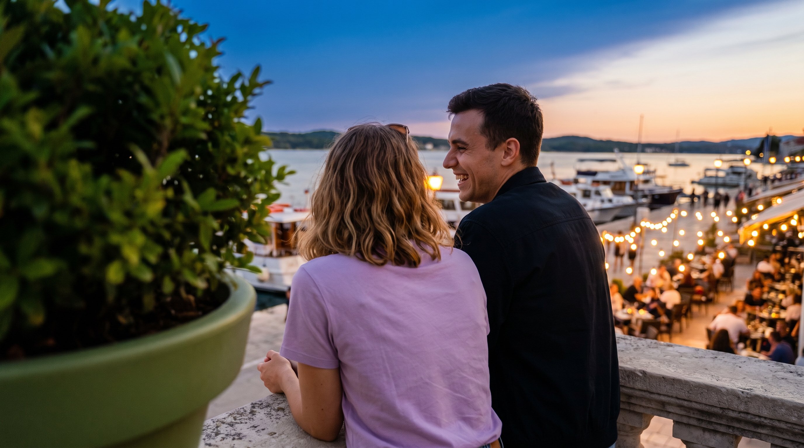 A couple in their 20s laughing together on a waterfront promenade in the evening