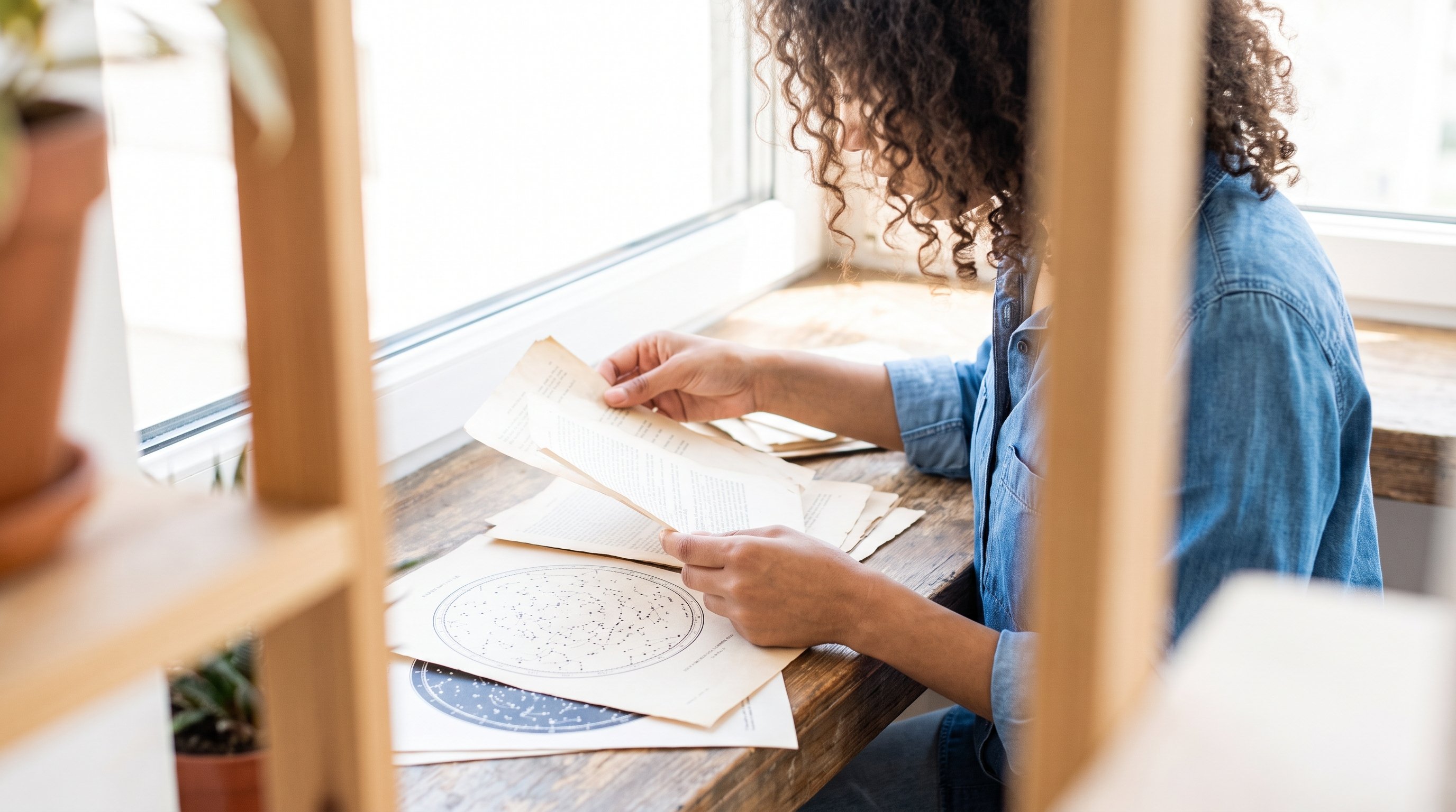 person reviewing notes at a desk near a window