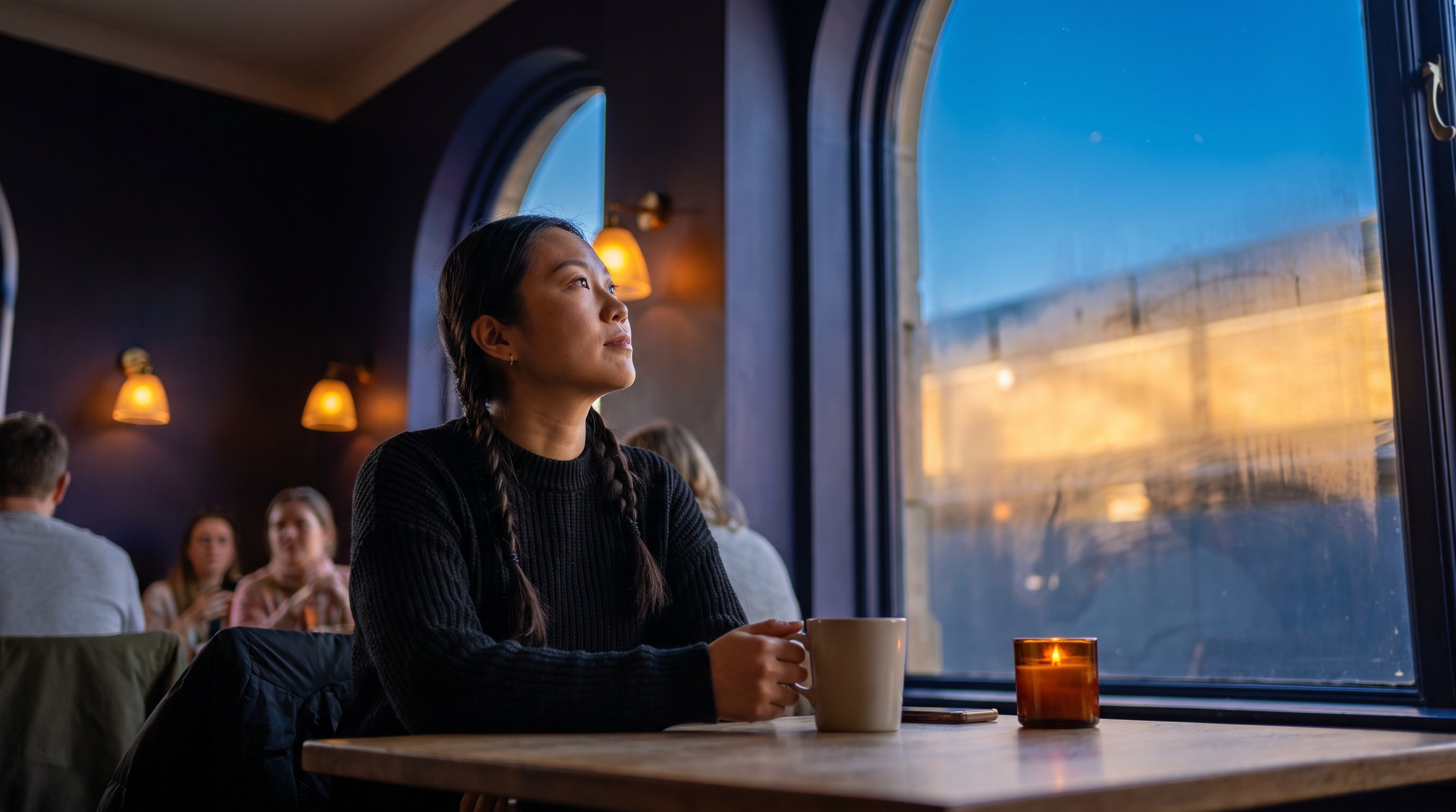 A reflective woman in her 30s looking up at a starry sky by a lake at dusk