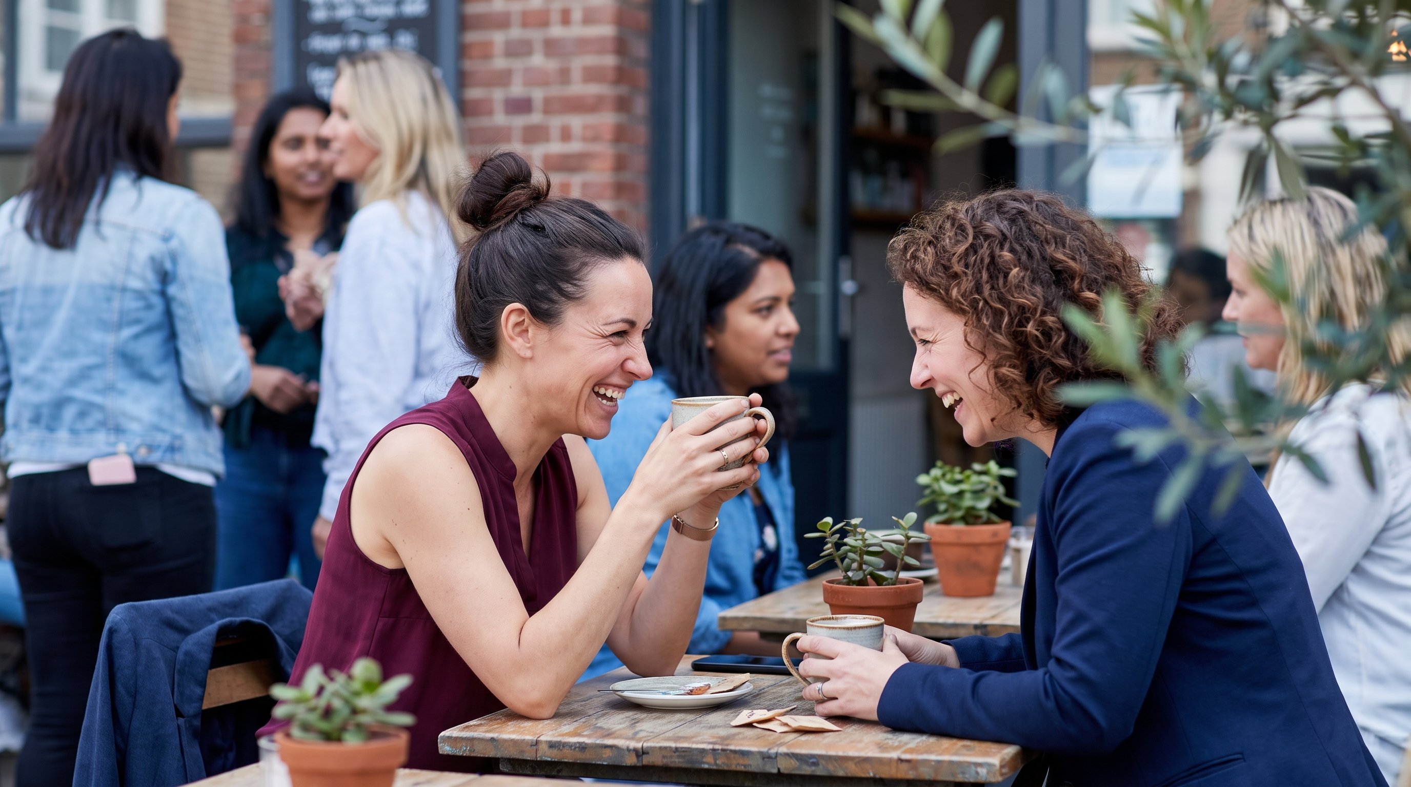 two people laughing together at an outdoor cafe table