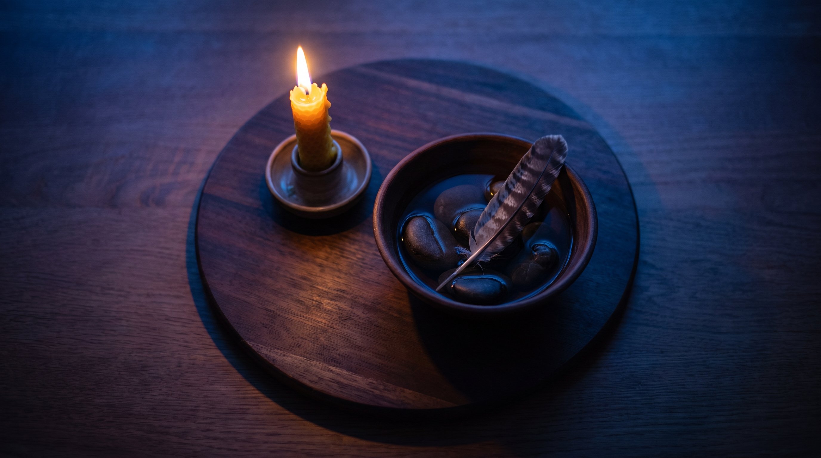 four candles water stones feather arranged on wooden table